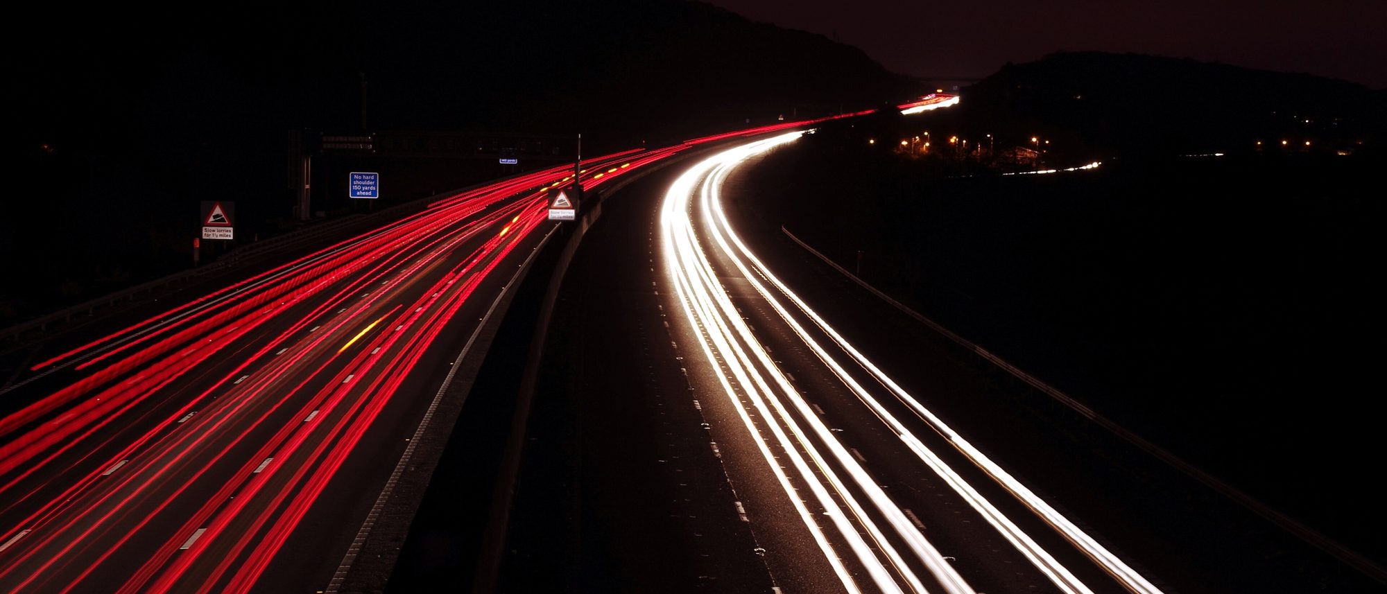 Autopista de noche con largas estelas de luz de los faros de los vehículos